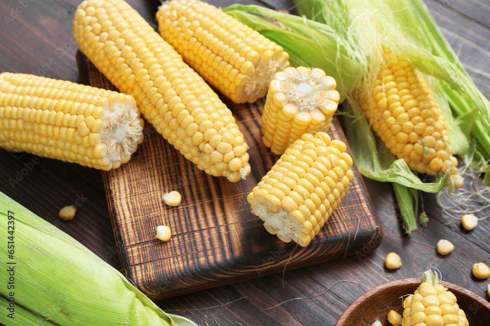 Fresh corn cobs on dark wooden table, closeup