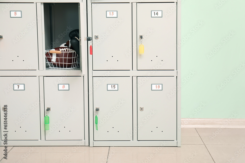 Modern locker with sports equipment near green wall