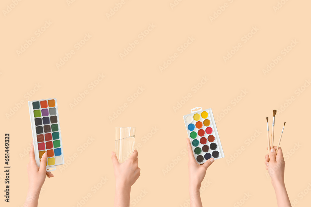 Female hands with artists supplies on beige background