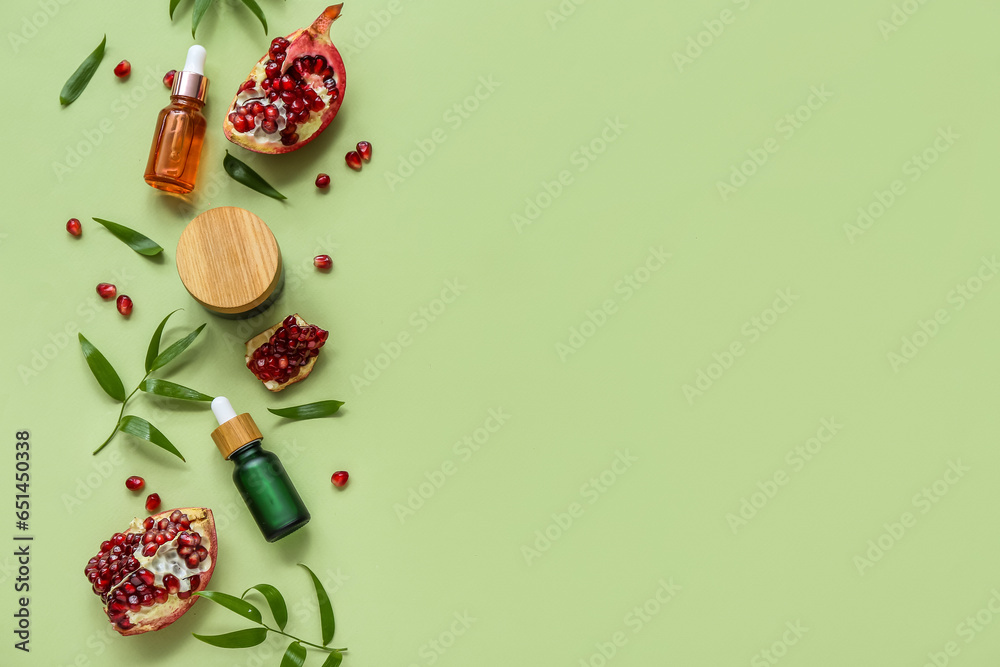 Composition with cosmetic products, pomegranate and plant leaves on green background