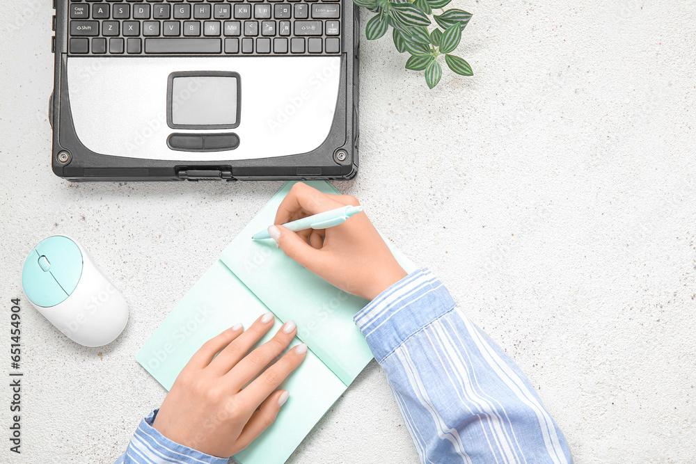 Woman working with old laptop and notebooks at white table in office