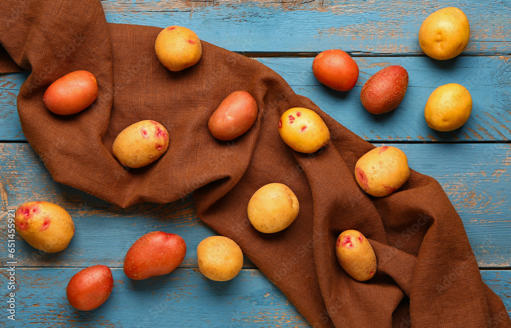 Fresh raw potatoes on blue wooden background