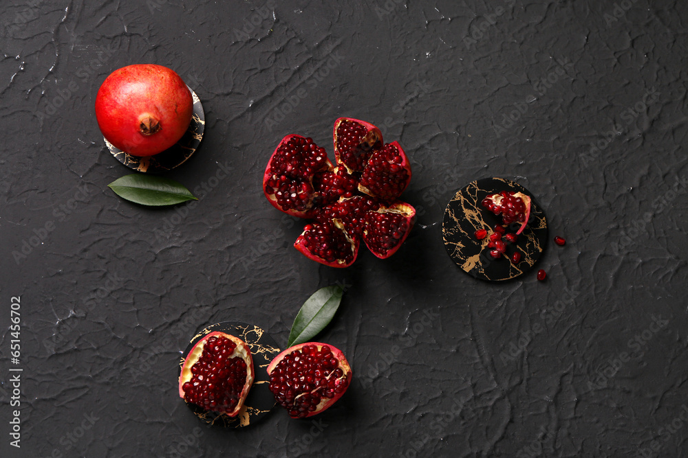 Fresh pomegranates and leaves on black background