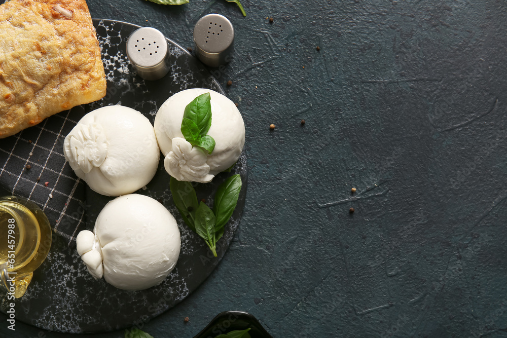 Board of tasty Burrata cheese with basil and bread on dark background