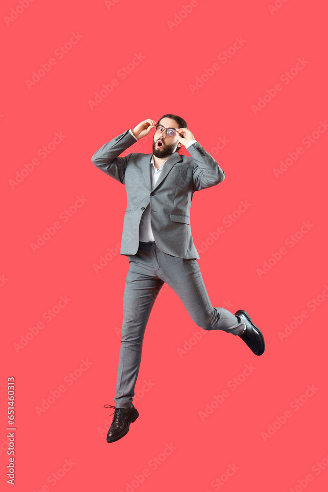 Jumping surprised businessman on red background