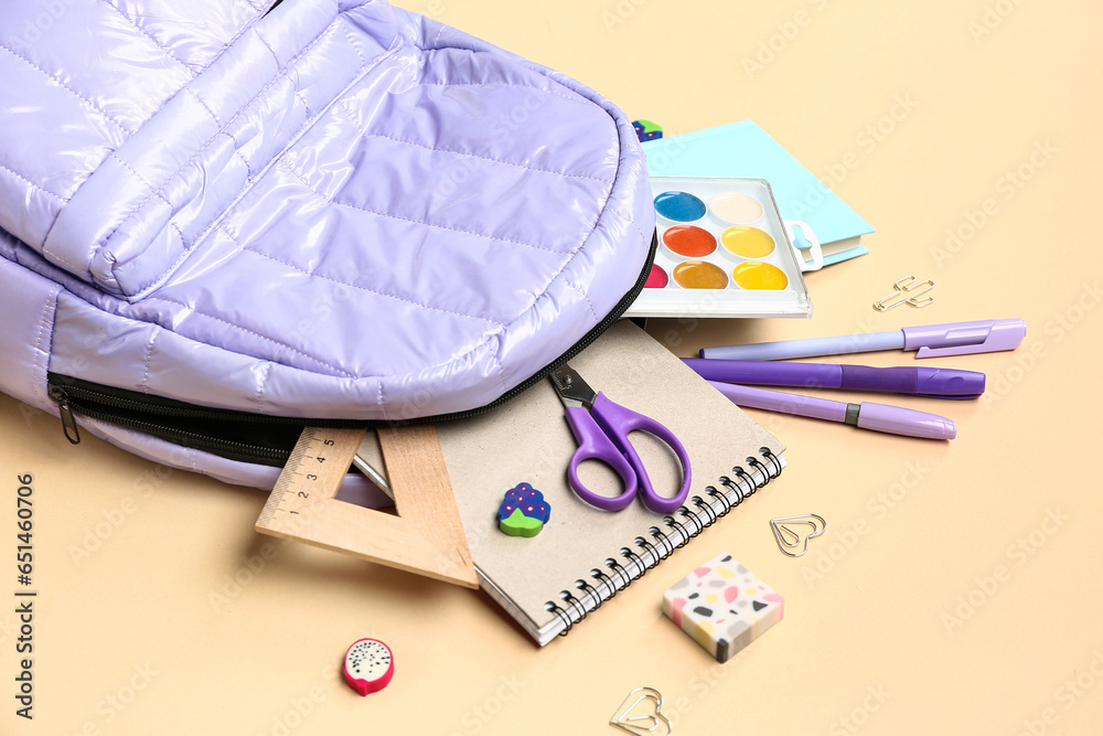 Stylish school backpack with different stationery supplies on beige background