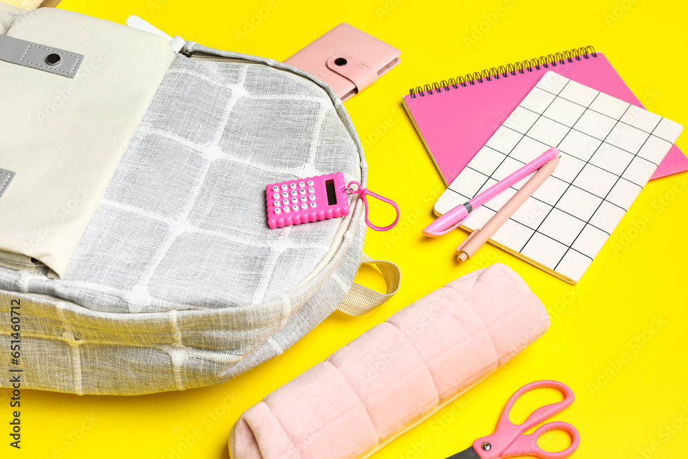 Stylish school backpack with different stationery supplies on yellow background