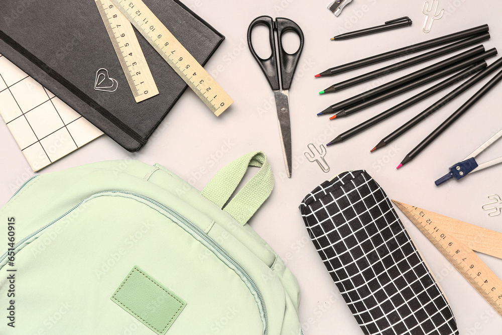 Stylish school backpack and pencil case with different stationery supplies on white background