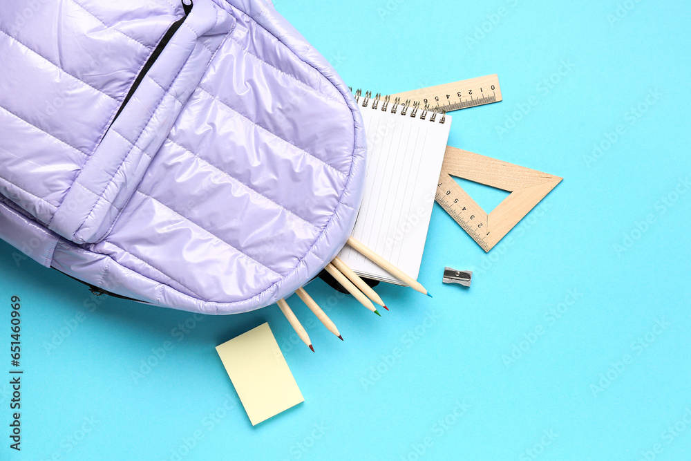 Stylish school backpack with different stationery supplies on blue background