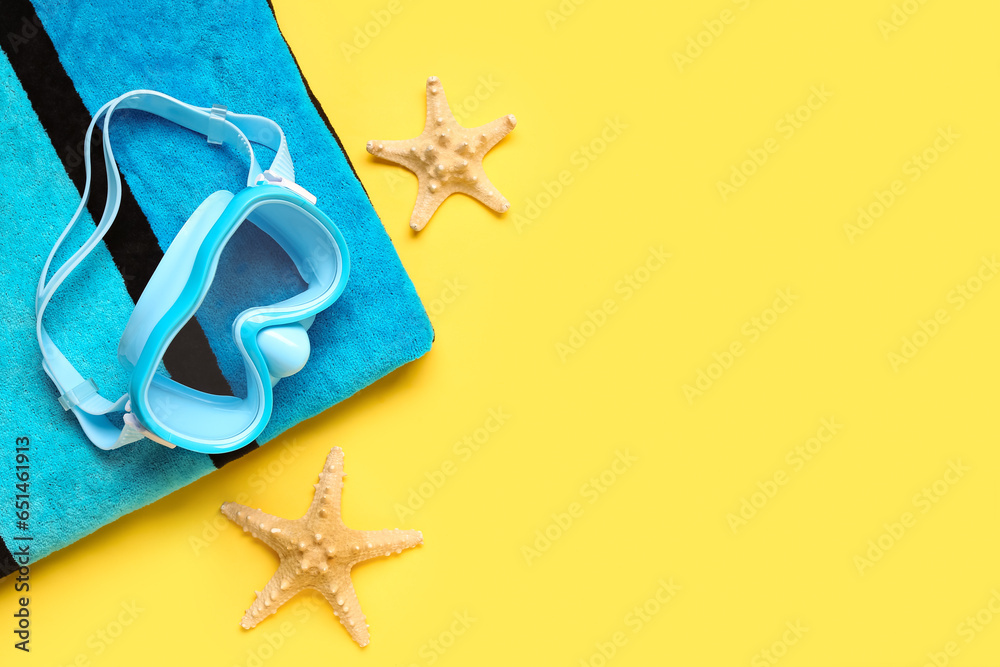 Swimming mask, towel and starfish on yellow background