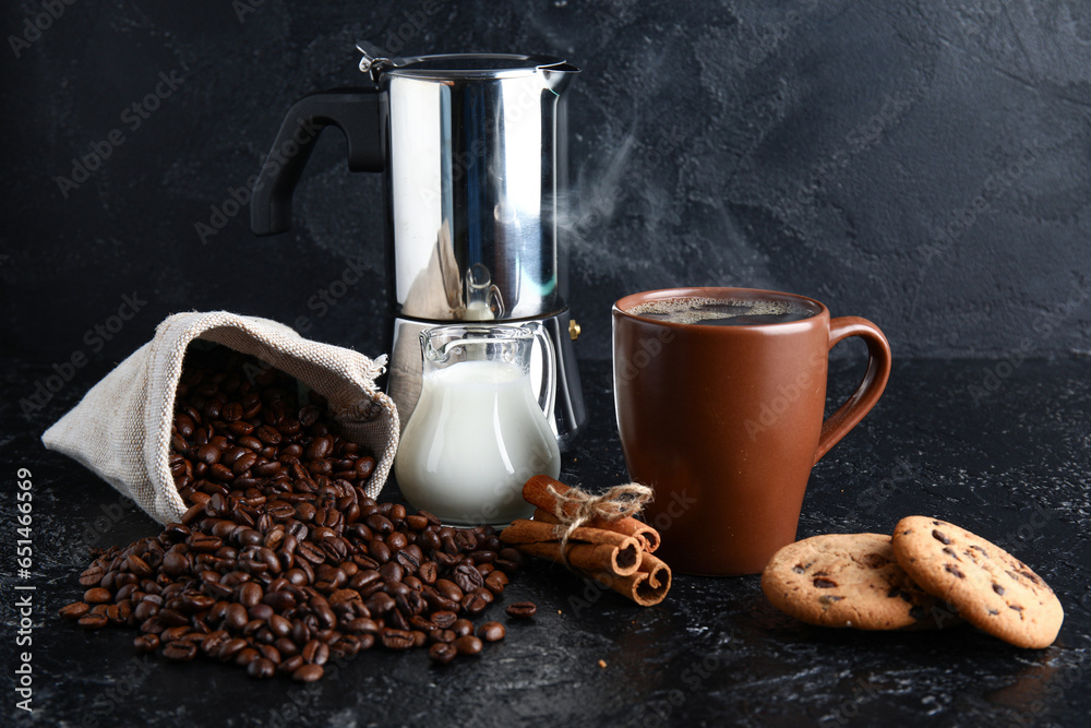 Cup of tasty coffee with cinnamon, beans, milk and cookies on black background