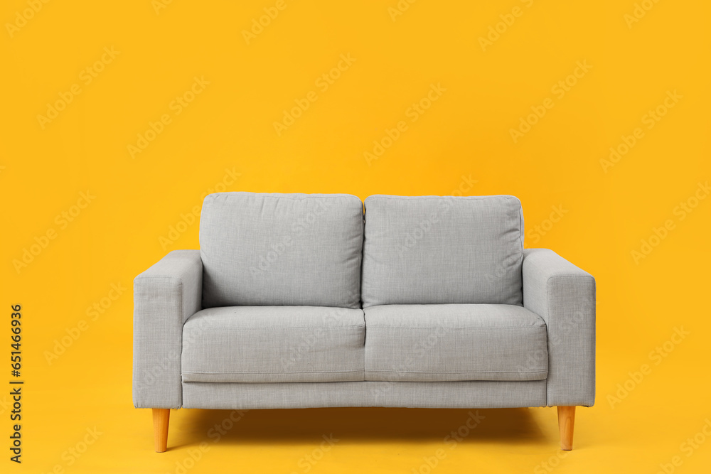 Cozy grey sofa on yellow background