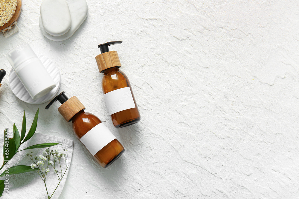 Bottles of shampoo, spa stones and cosmetic products on white background