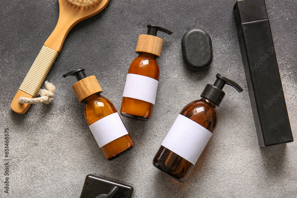 Bottles of shampoo, spa stone and brush on grey background