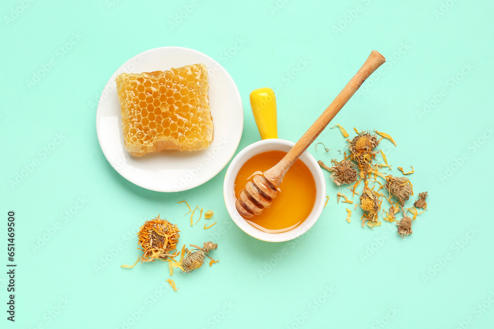 Bowl with tasty honey, honeycomb, dipper and dried dandelion flowers on turquoise background