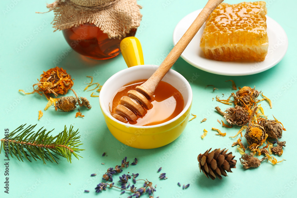 Bowl with tasty honey, dipper, honeycomb and dried flowers on turquoise background, closeup