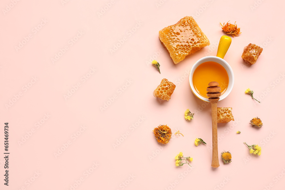 Bowl with tasty honey, honeycomb, dipper and beautiful flowers on pink background