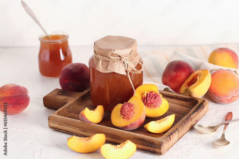 Jar with sweet peach jam and fresh fruits on light background