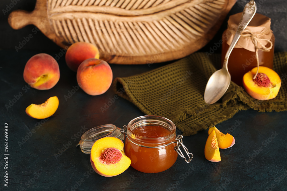 Jar with sweet peach jam and fresh fruits on black background