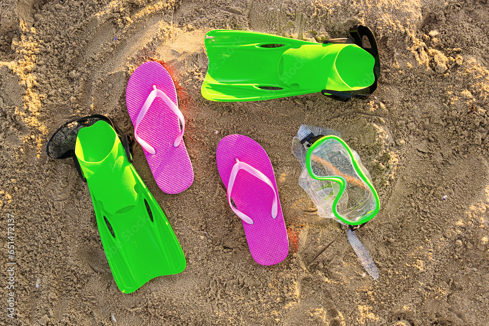 Stylish female flip flops, flippers and snorkeling mask on sand