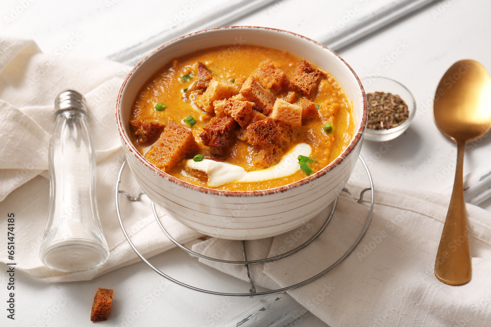 Bowl of tasty cream soup with croutons on white wooden background