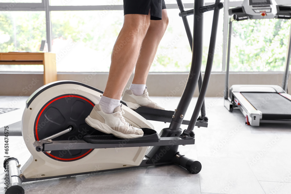 Sporty mature man training on elliptical trainer at home, closeup