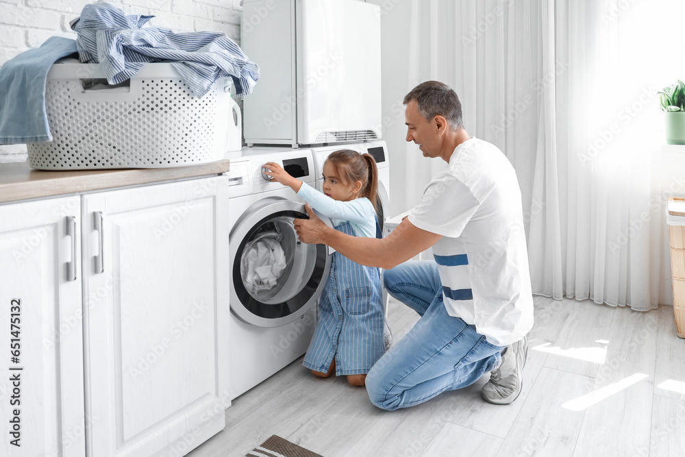 Mature man with his little granddaughter doing laundry at home