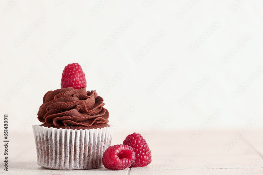 Tasty chocolate cupcake with raspberries on table