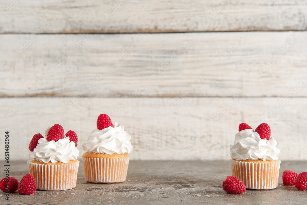 Tasty raspberry cupcakes on table