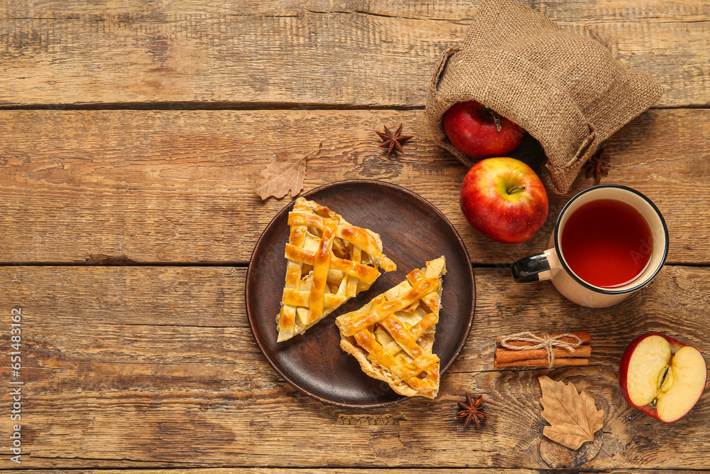 Plate with pieces of delicious apple pie and cup of hot tea on wooden background