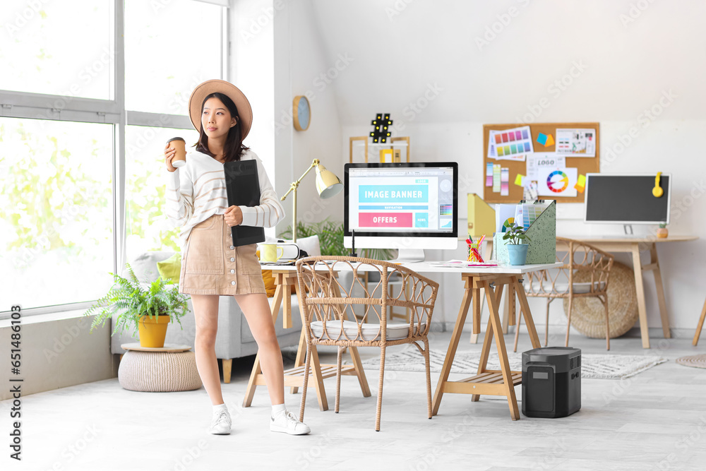 Asian interior designer with graphic tablet and cup of coffee in office