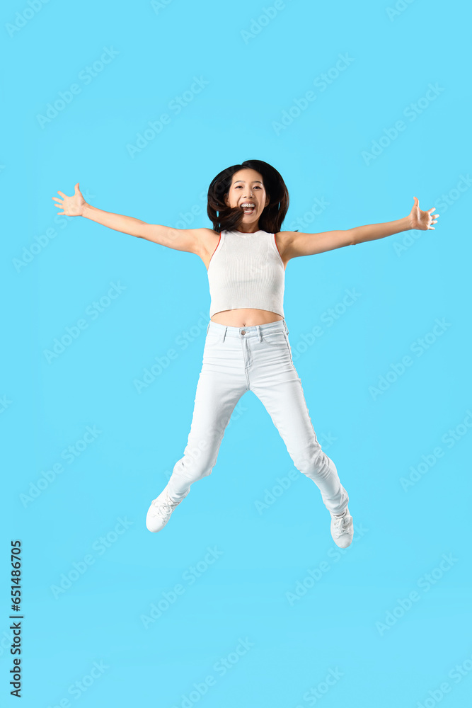 Jumping Asian woman on blue background