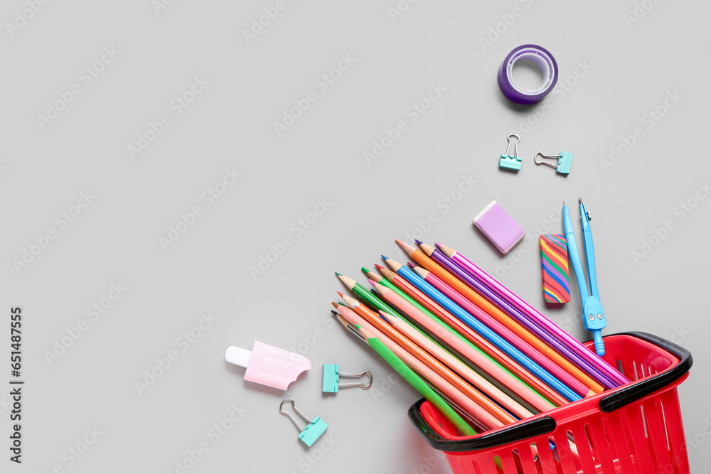 Shopping basket with different school stationery on grey background