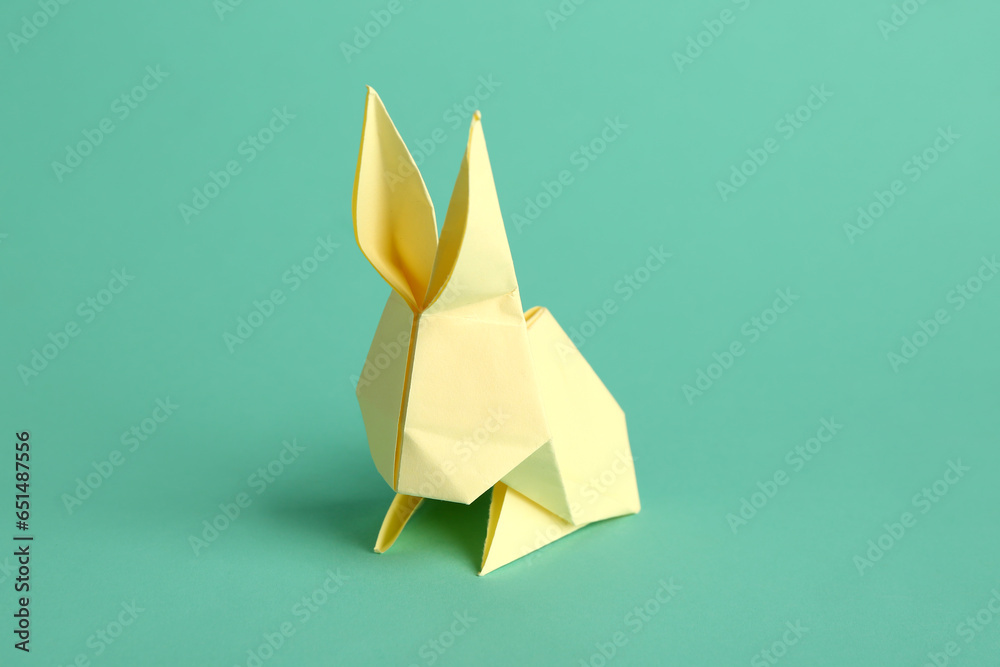 Beige origami rabbit on turquoise background