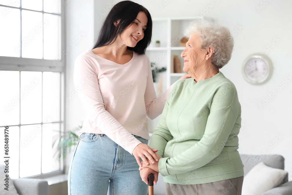 Senior woman with walking stick and her daughter at home