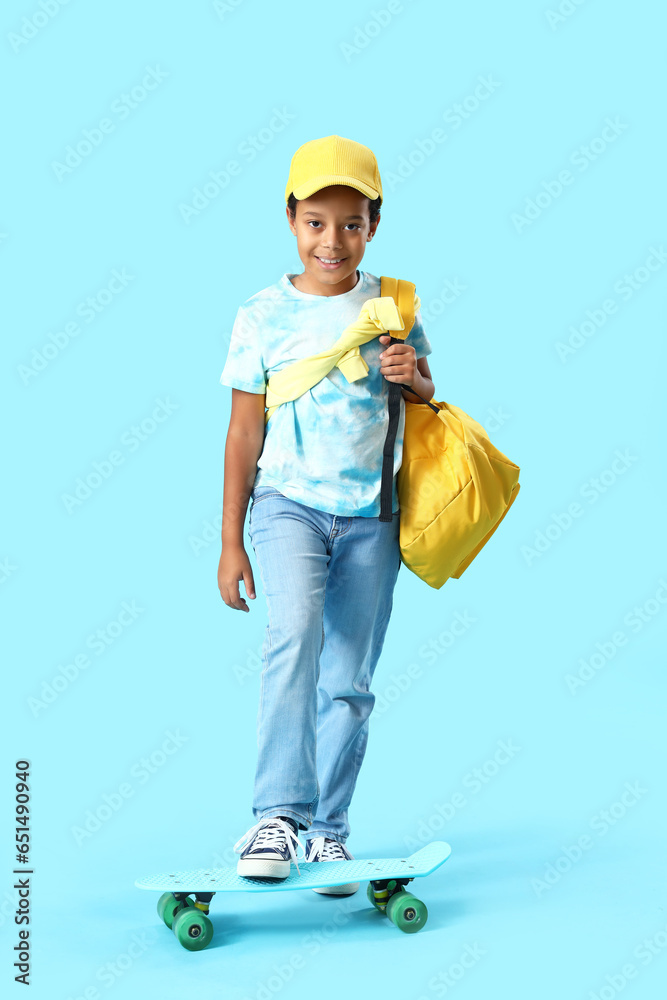 African-American little boy with skateboard on blue background