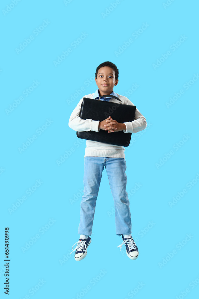 African-American little boy with briefcase jumping on blue background