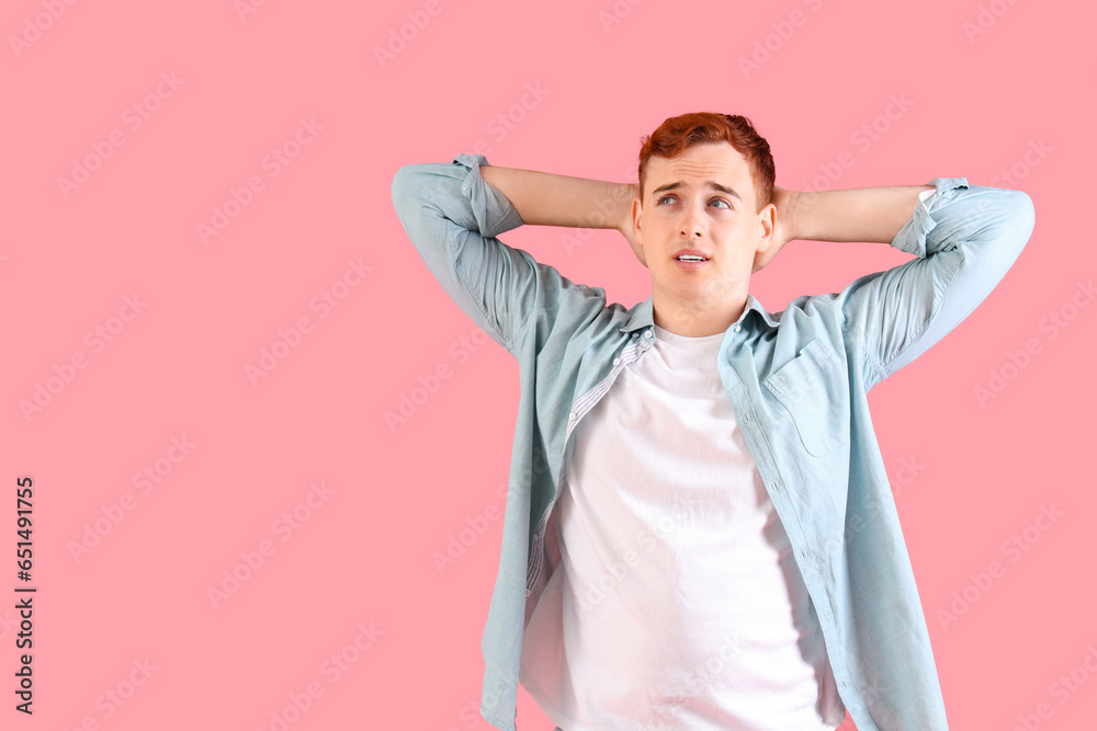 Thoughtful young redhead man on pink background