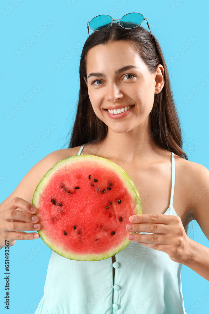 Beautiful young woman with slice of fresh watermelon on blue background