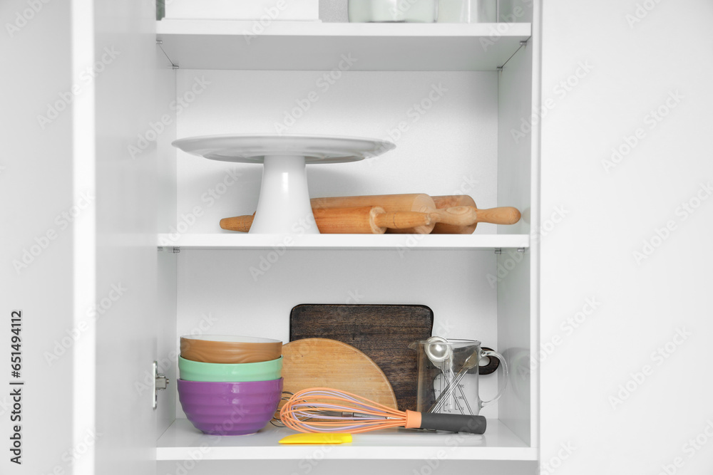 Cupboard with set of utensils for bakery in kitchen