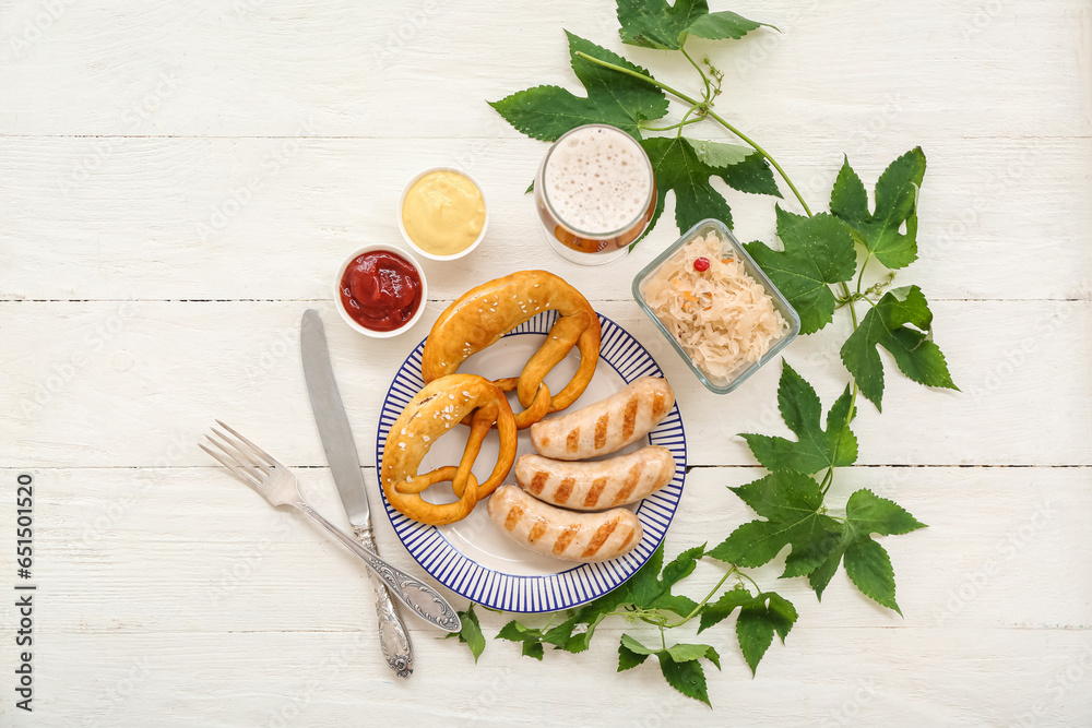 Plate with tasty Bavarian sausages, pretzels, sauces, sauerkraut and glass of beer on white wooden background. Oktoberfest celebration