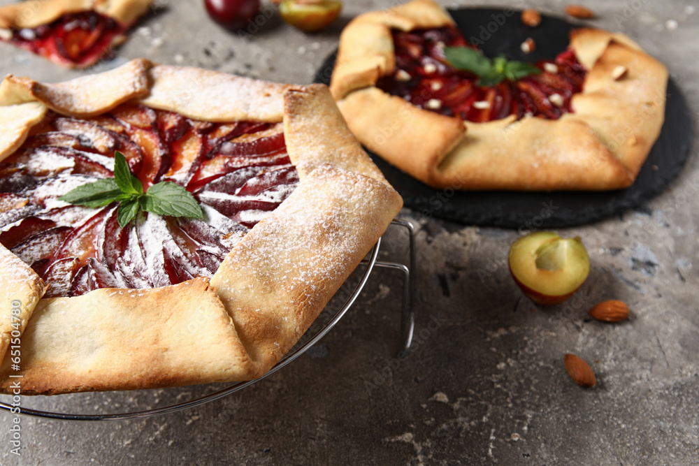 Stand with delicious plum galette on grey background