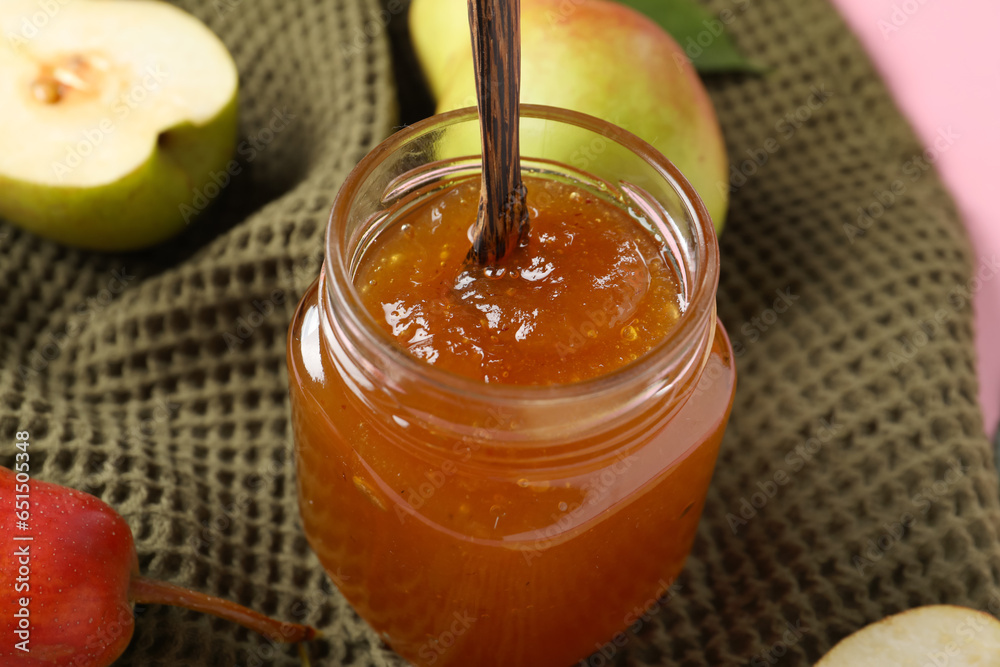 Glass jar of tasty pear jam on fabric background