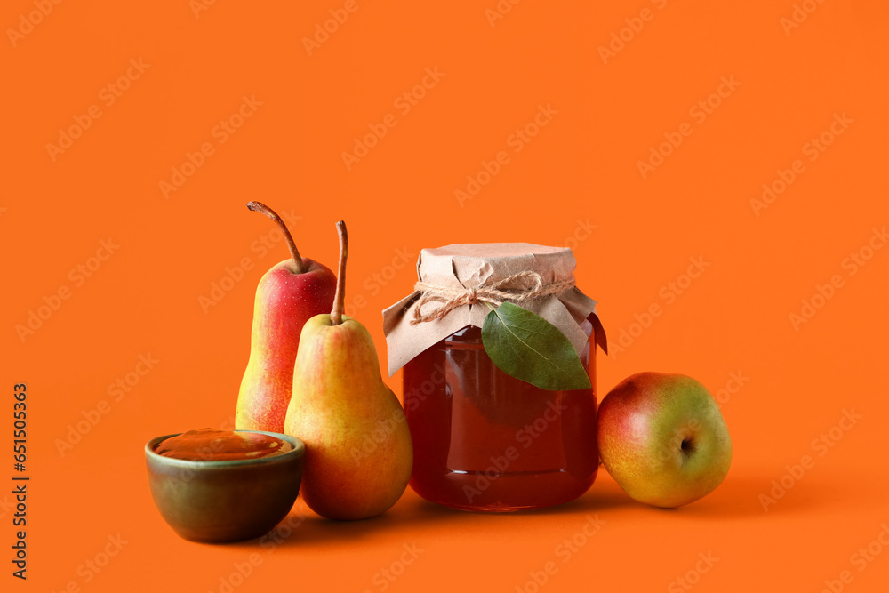 Glass jar and bowl of tasty pear jam on orange background