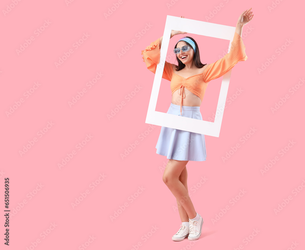 Beautiful young woman with frame on pink background