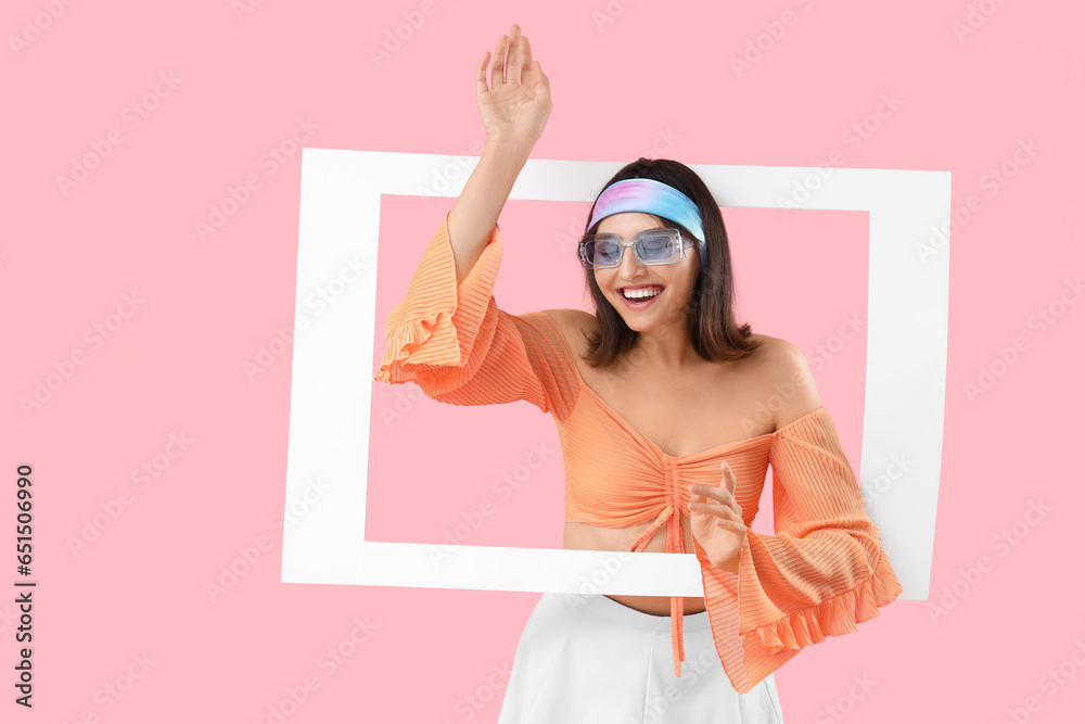 Beautiful young woman with frame on pink background