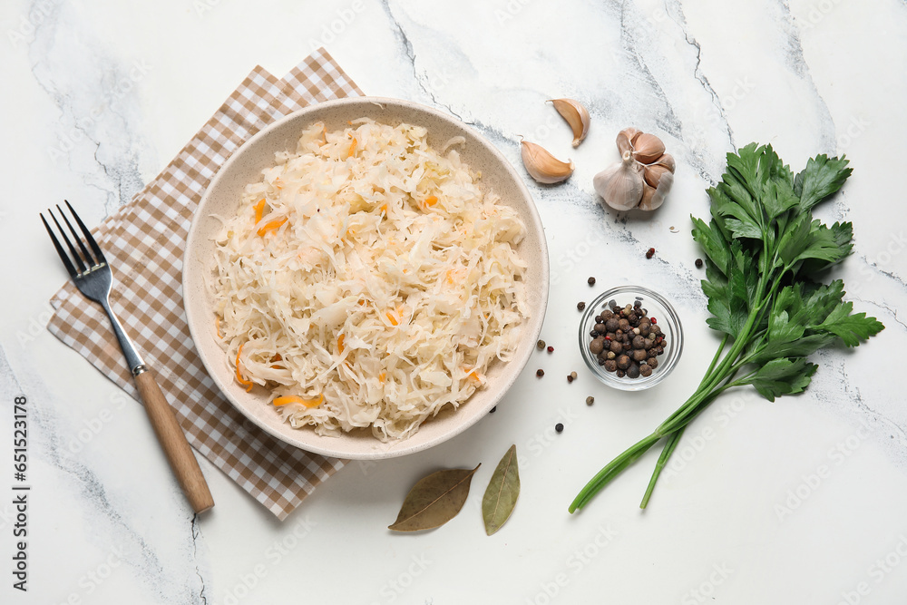 Bowl with delicious sauerkraut and different spices on white background