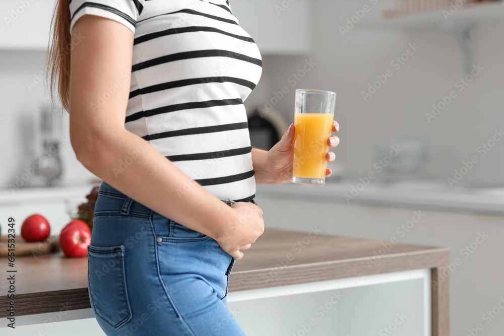 Young pregnant woman with glass of juice in kitchen, closeup