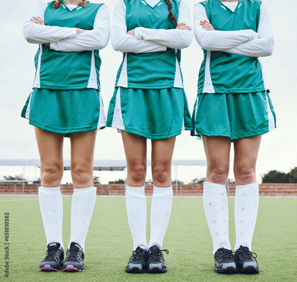 Legs, arms crossed and a woman hockey team outdoor on a field for a game or competition together in summer. Fitness, feet and sports people on a pitch of a grass for training or teamwork on match day