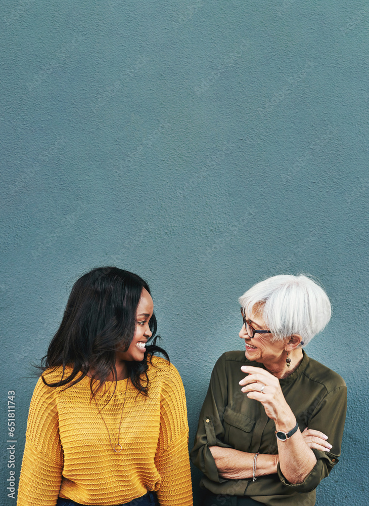 Happy, conversation and women by a wall with mockup space for advertising, promotion or marketing. Smile, talking and female people in discussion together with comic or funny joke by gray background.